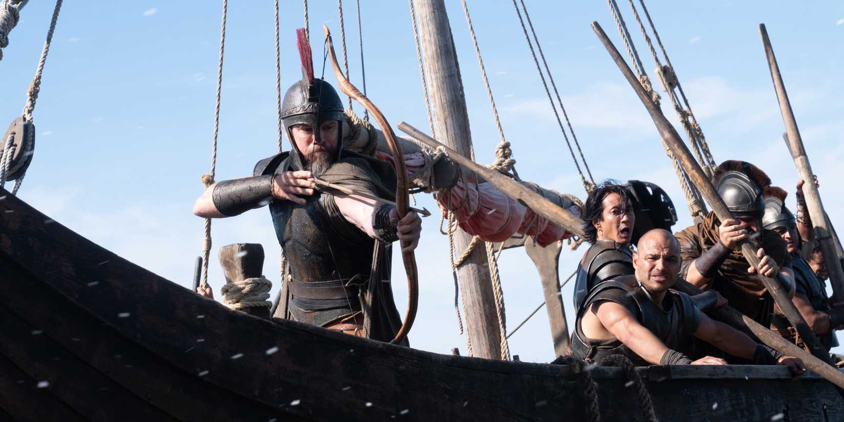 Odysseus (Matt Damon) on a ship with his men wielding a bow and arrows in The Odyssey (2026).