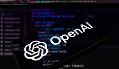 The OpenAI logo is displayed on a smartphone screen placed on a reflective surface onto which lines of computer code.