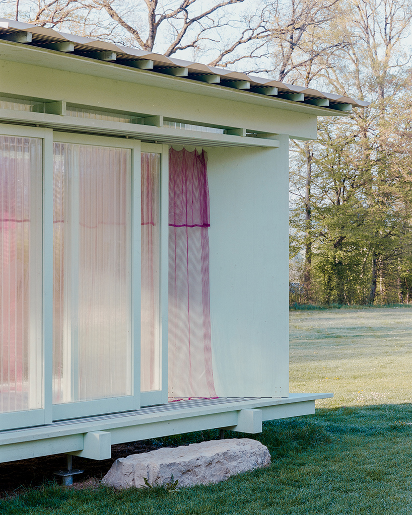 sliding timber frames and reused materials shape reversible pavilion within swiss meadow - 4