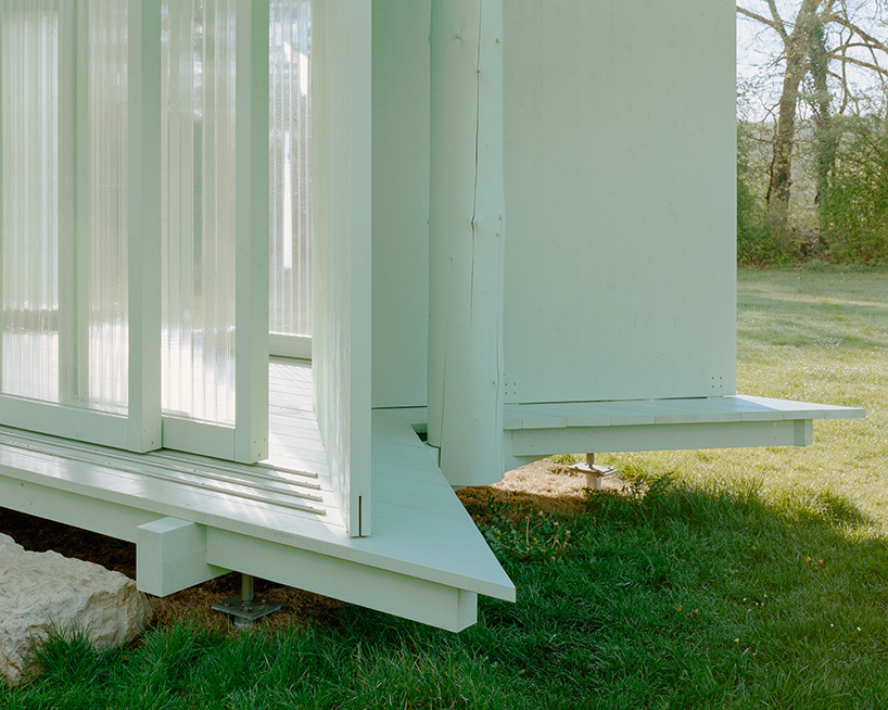 sliding timber frames and reused materials shape reversible pavilion within swiss meadow - 5