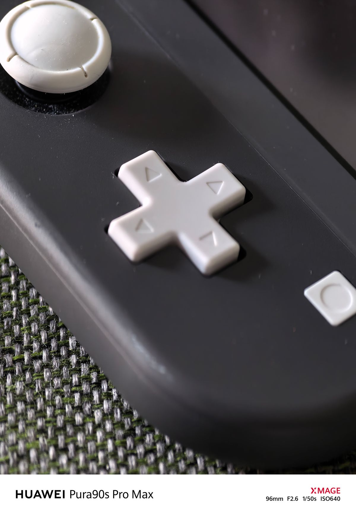 Close-up of a black game controller with contrasting white joystick, directional pad and buttons.