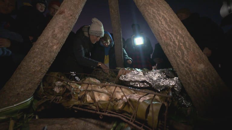 People pick food from the umu kohukohu for Matariki hautapu celebrations hosted by Ngāti Whātua in 2022.