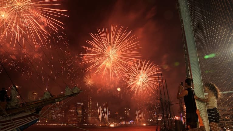 People watch fireworks explode over the New York City skyline as seen from the Brooklyn Borough of New York.