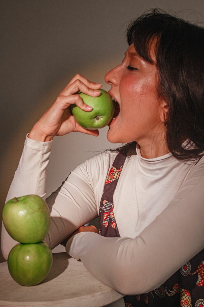 A woman biting a green apple, representing a patient interaction with ER staff.