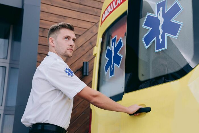 An ER staff member in uniform opening an ambulance door, ready to deal with patients.