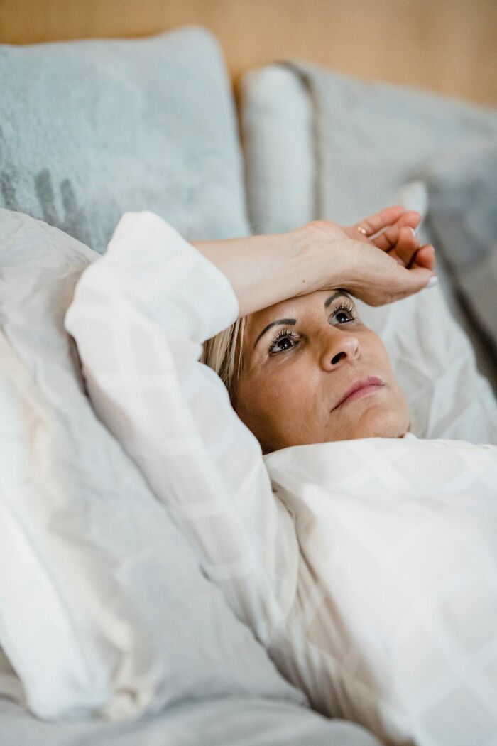 A woman with her hand on her forehead, looking troubled, portraying a patient experience with ER staff.