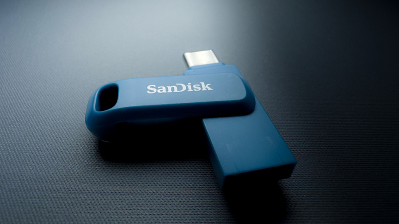 A blue SanDisk flash drive with its protective cover exposing a silver USB-C connector.