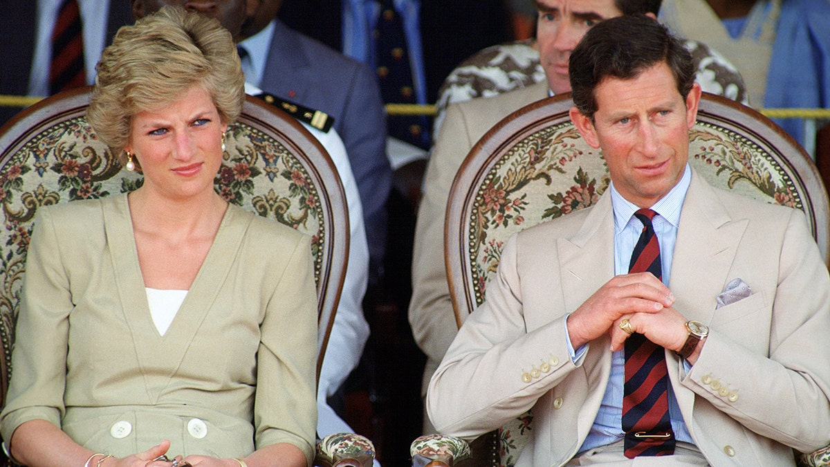 Prince Charles and Princess Diana standing outdoors wearing matching tanned suits.