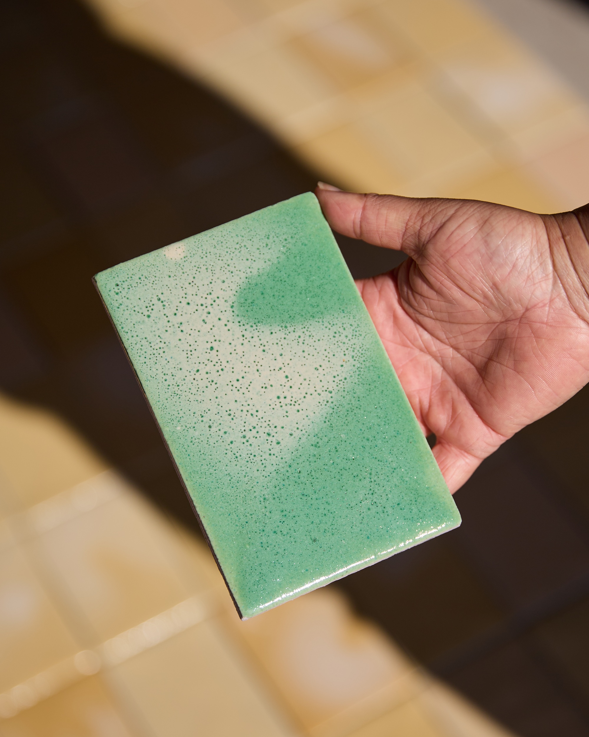 a bright green speckled tile in a hand