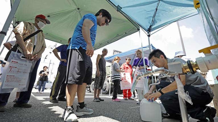 Residents receive water supplies at Hikawa town hall as an earthquake disrupted water service in Hikawa, Kumamoto Prefecture, southern Japan, Friday, July 31, 2026.