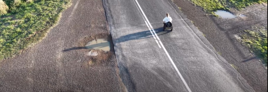 woman in wheelchair on lonely stretch of road