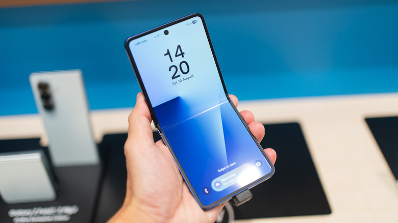 A person holding the Samsung Galaxy Z Flip7 smartphone in a half-folded state