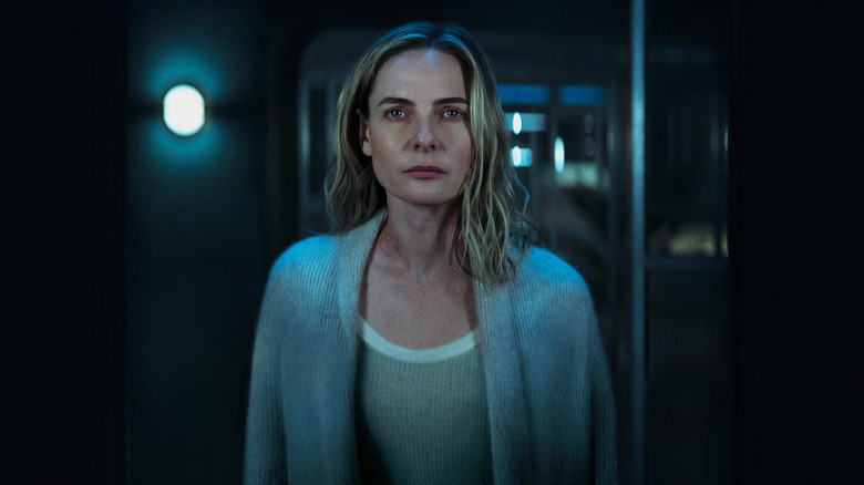 Rebecca Ferguson as Juliette Nichols in Silo stands in a dimly lit room wearing a gray cardigan.