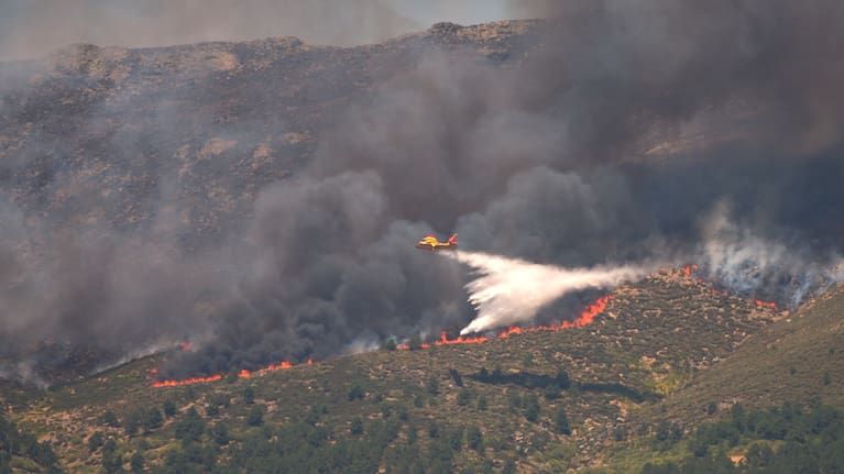A seaplane drops water onto the fire as a wildfire advances near La Adrada, Ávila province, Spain, Friday, July 24, 2026.