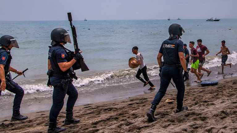 Spanish police officers respond as migrants cross from Morocco into the Spanish enclave of Ceuta, Thursday, July 30, 2026.