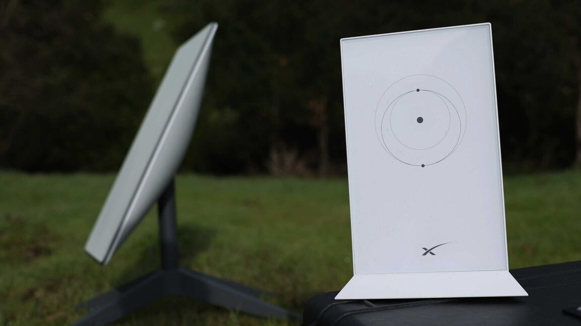 Picture of a Starlink satellite dish and router placed outside, on a lawn.