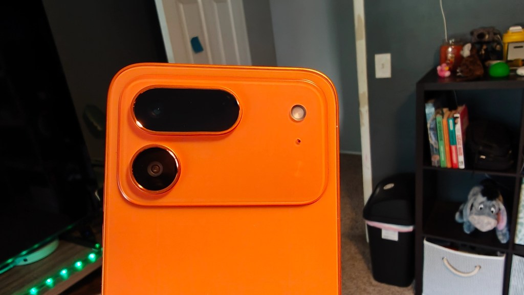 Close-up view of an orange smartphone's back, showcasing its dual camera setup and an additional sensor.