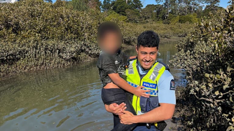 The boy is carried out of the mangroves by a police officer.