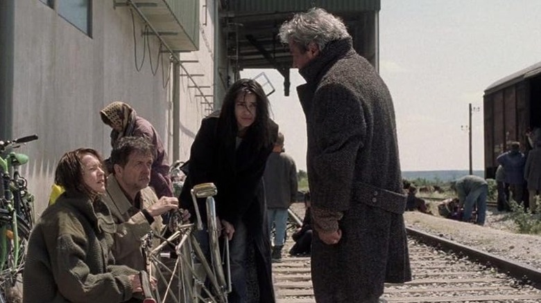 Anne Laurent and her family on a train track talking to a man in a coat in Time of the Wolf