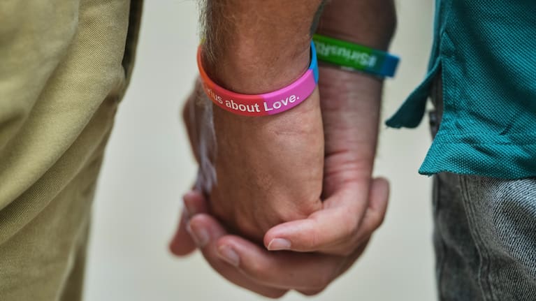 Two men hold hands at the memorial site commemorating the victims near the scene where a car rammed into a crowd near the Pride March in Berlin.