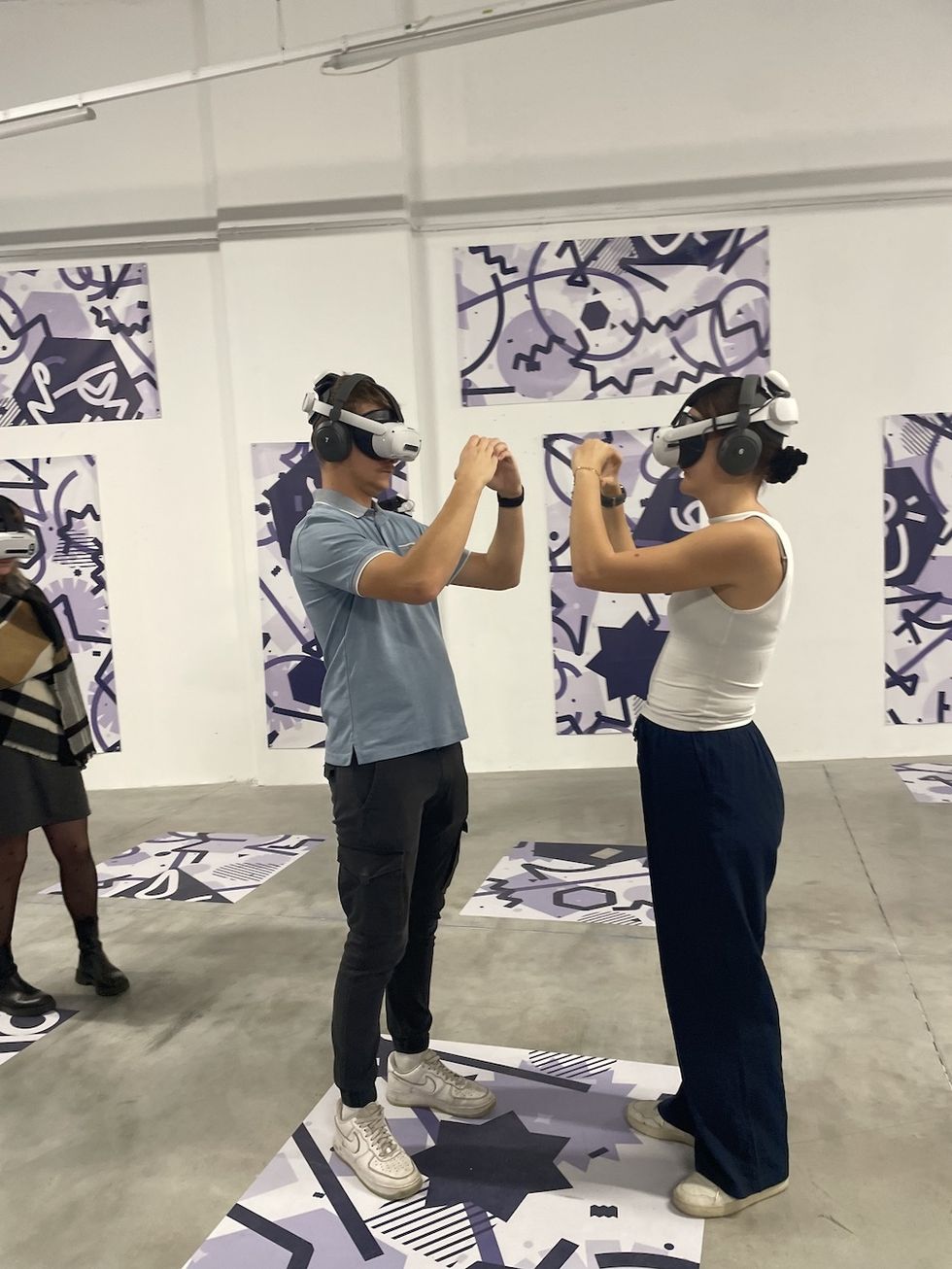 Two people wearing VR headsets interact in a modern art gallery.