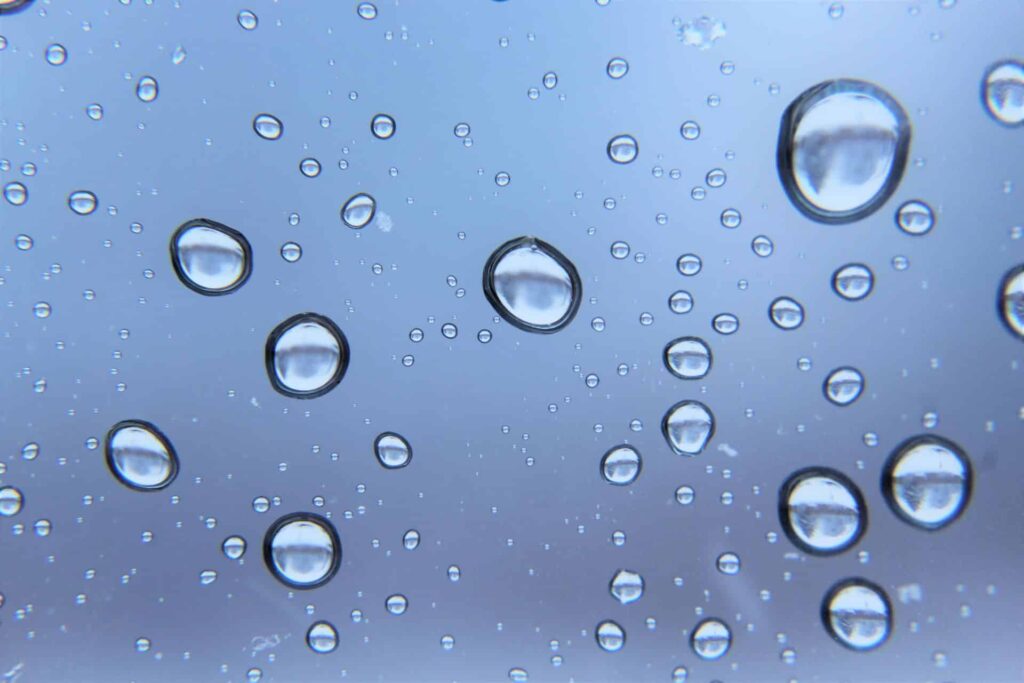 Close-up of water droplets on a glass surface with a blue background.