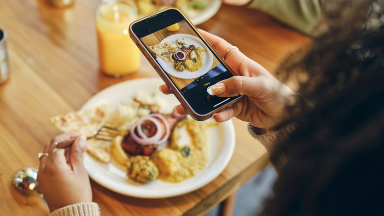 A person clicking the photo of the food kept in front of them