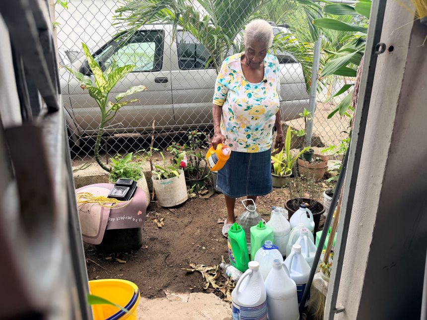 Milagros Pica Quiñones, 96, looks at the bottles she uses to collect potable water.