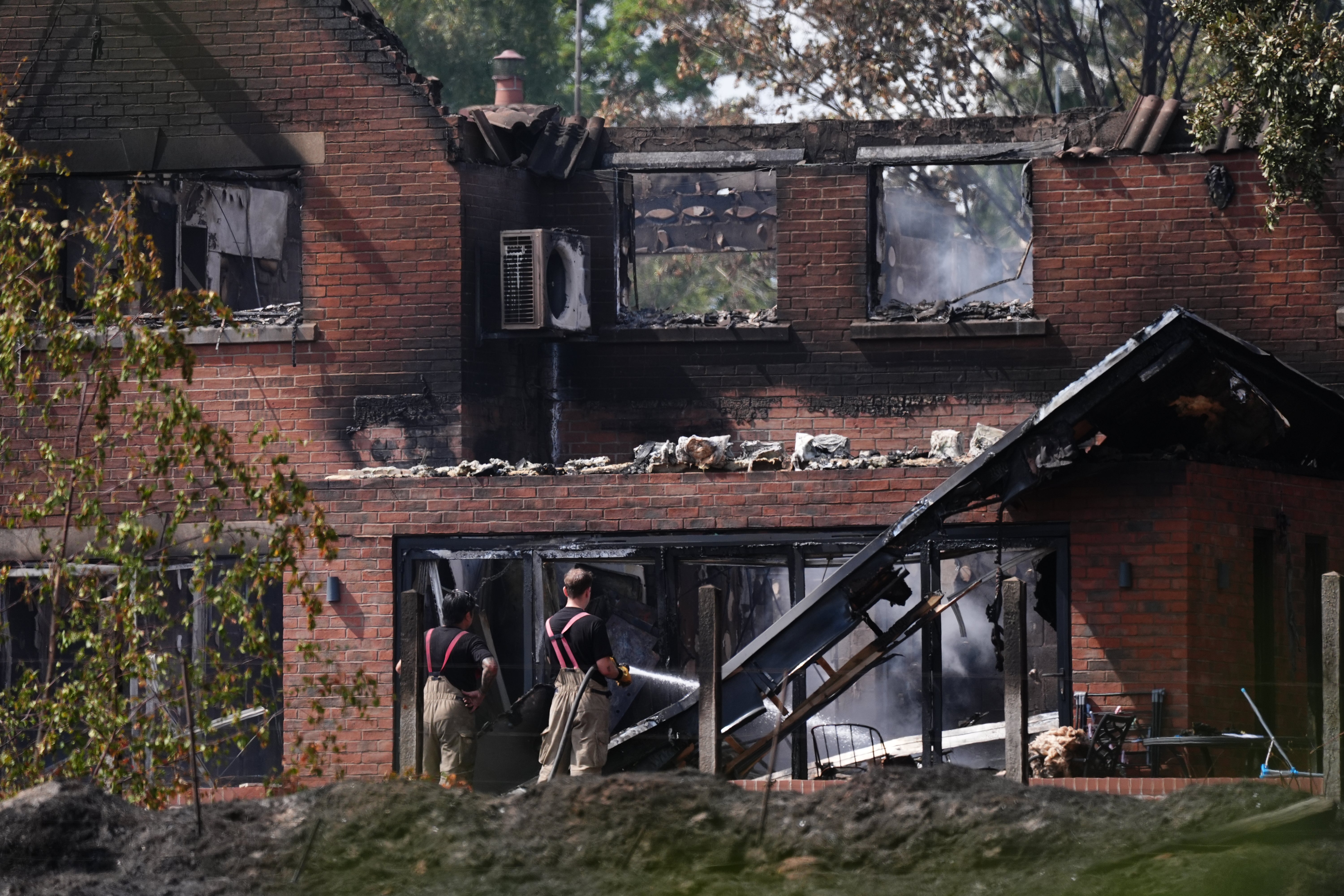 Firefighters looking at the burnt-out remains of a house following a blaze in Stourbridge