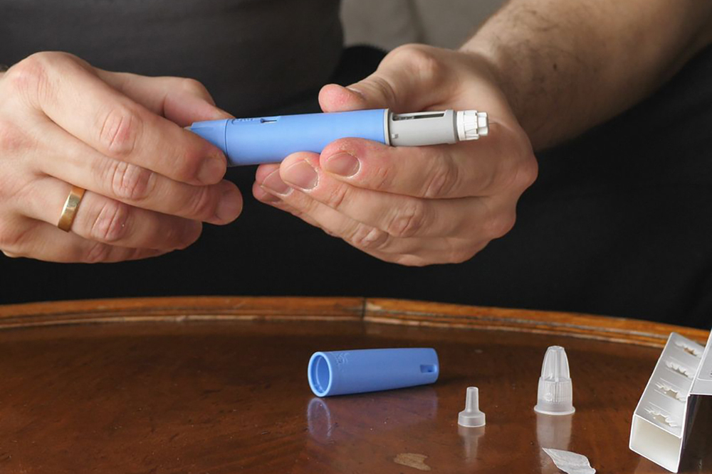 A man holds an injector for a weight-loss drug.