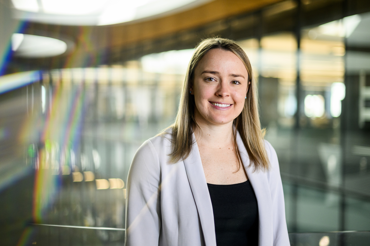 Lauren Raine, smiling, standing in a sunlit modern building. 