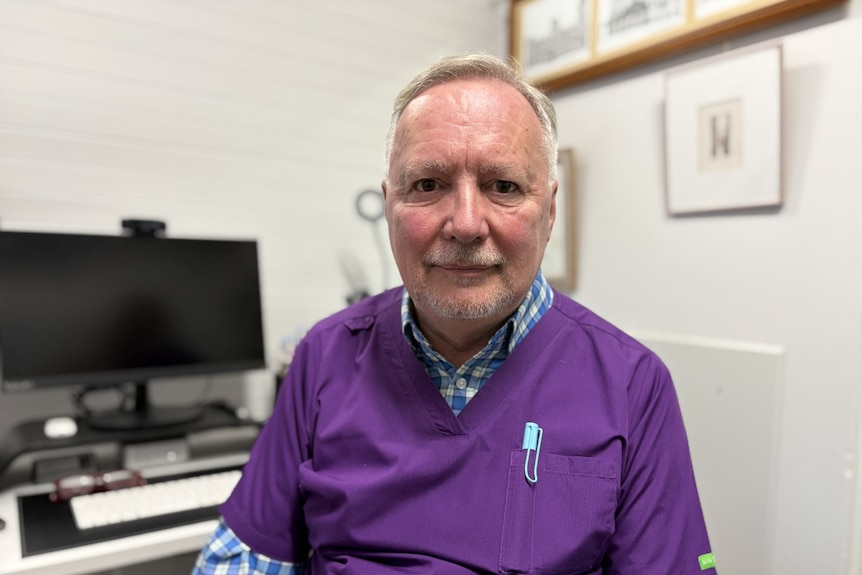 A man in a shirt with purple scrubs over the top