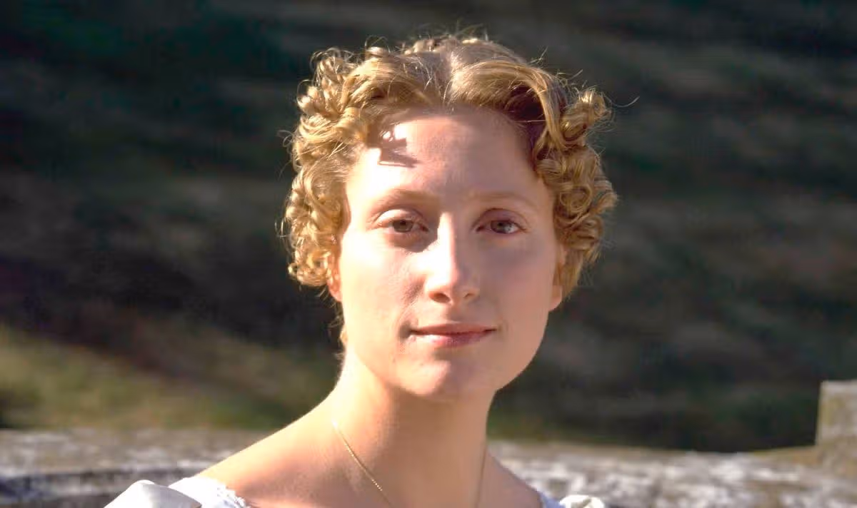 A blonde woman smiles outside