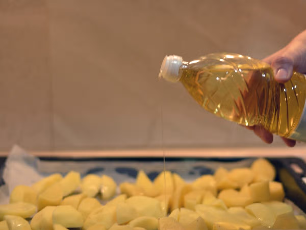 Woman adding oil to potatoes