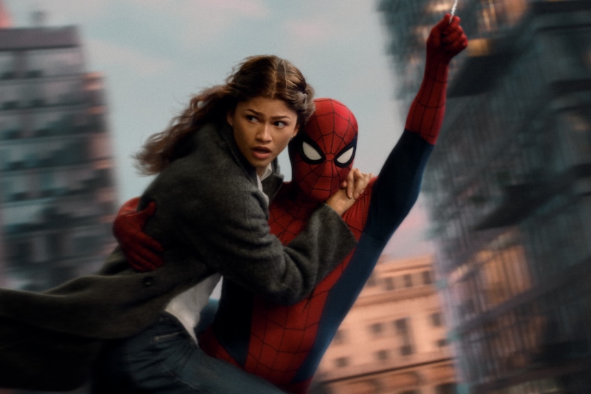 Zendaya - a mixed Black woman being rescued on the side of a building by a man - Tom Holland - in a red and blue Spider-Man suit
