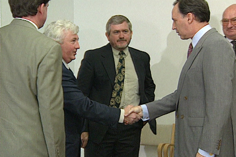 Two men in suits shake hands