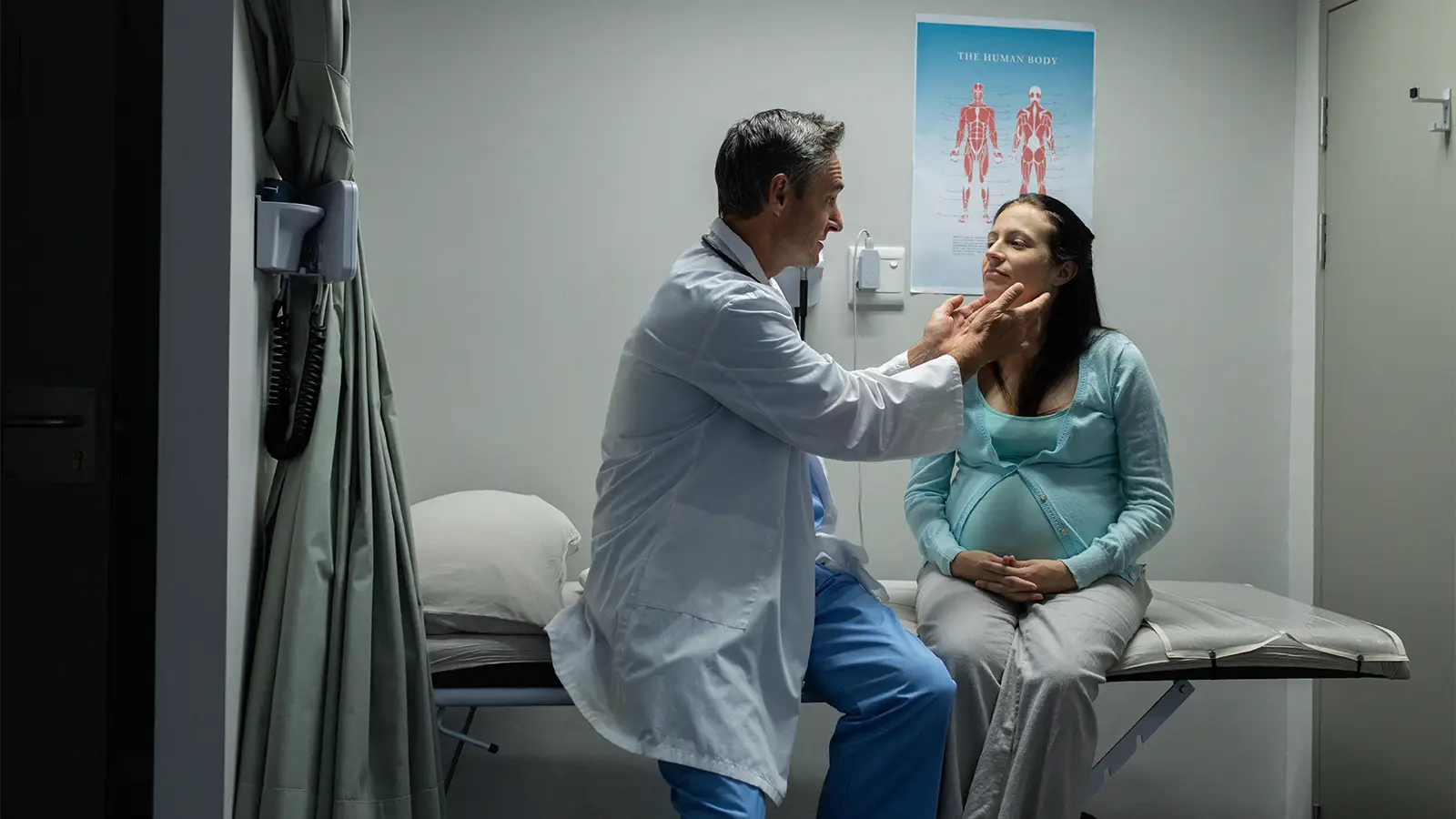 A photo of a male physician examining a pregnant woman.