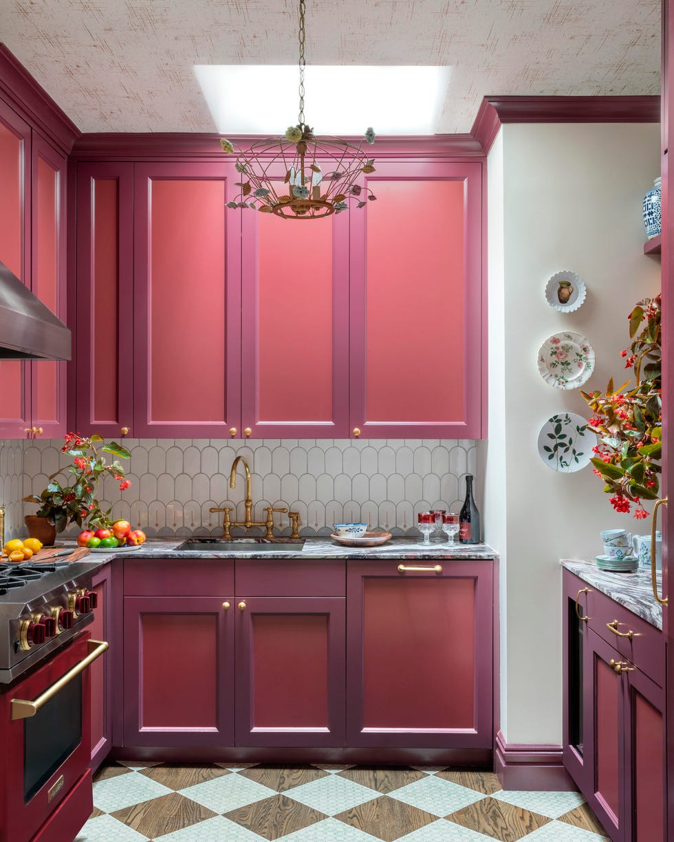 Stylish kitchen with pink cabinets, marble countertops, decorative plates, and a chandelier. Stylish kitchen with pink cabinets, marble countertops, decorative plates, and a chandelier.