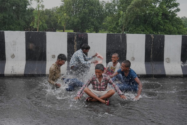 Children play in the rain on the highway during monsoon showers on the outskirts of Raebareli District, in the northern Indian state of Uttar Pradesh, Sunday, Aug. 2, 2026. (AP Photo/Rajesh Kumar Singh)