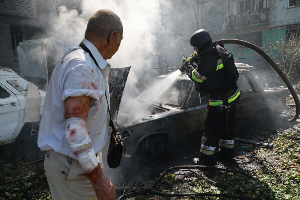 Rescue workers try to put out a fire of a residential building and cars burning after a Russian air guided bomb strike in Zaporizhzhia, Ukraine, Monday, Aug. 10, 2026. (AP Photo/Kateryna Klochko)