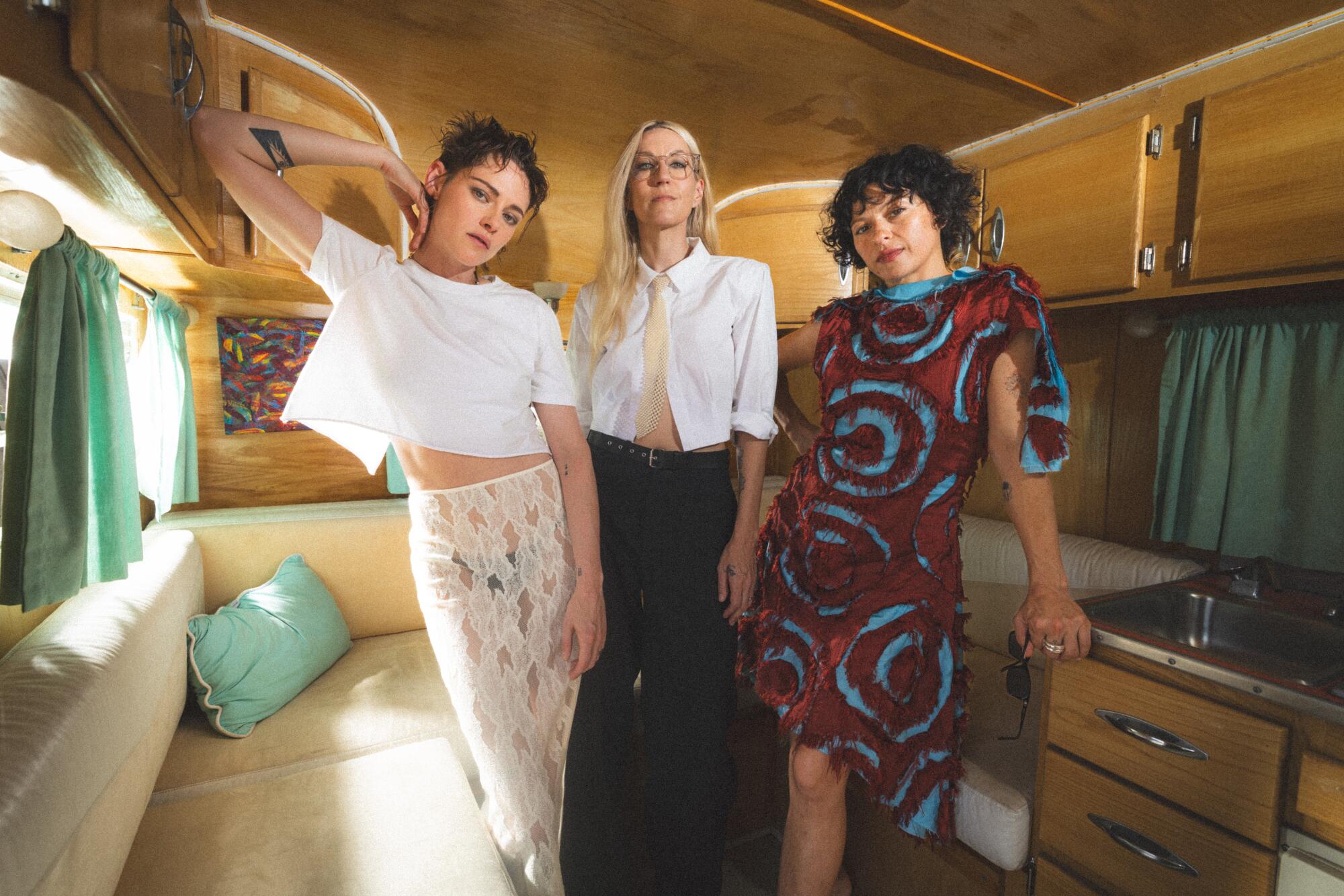 Three women stand inside a trailer.