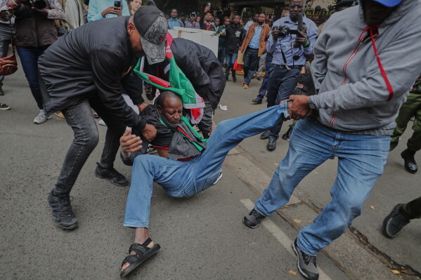 Police detain an activist during a demonstration over alleged abductions and extrajudicial killings, outside the office of Kenya's Inspector General of Police Douglas Kanja, in Nairobi, Kenya, Monday, Aug. 17, 2026. (AP Photo/Henry Naminde)