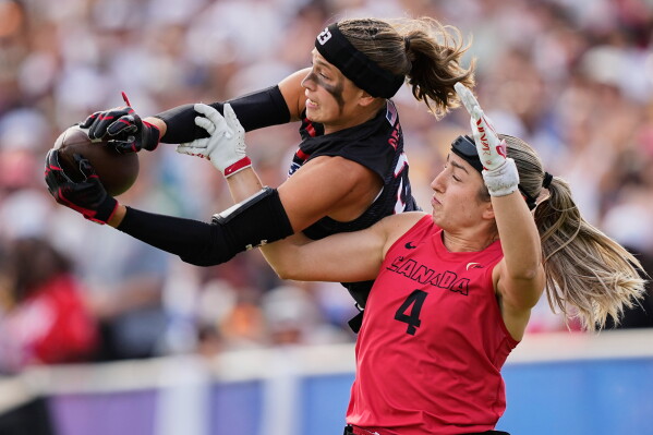 Isabella Geraci of the United States and Rosalie Landry of Canada challenge for the ball during the Flag Football World Championship women's final game between Canada and USA in Duesseldorf, Germany, Sunday, Aug. 16, 2026. (AP Photo/Martin Meissner)