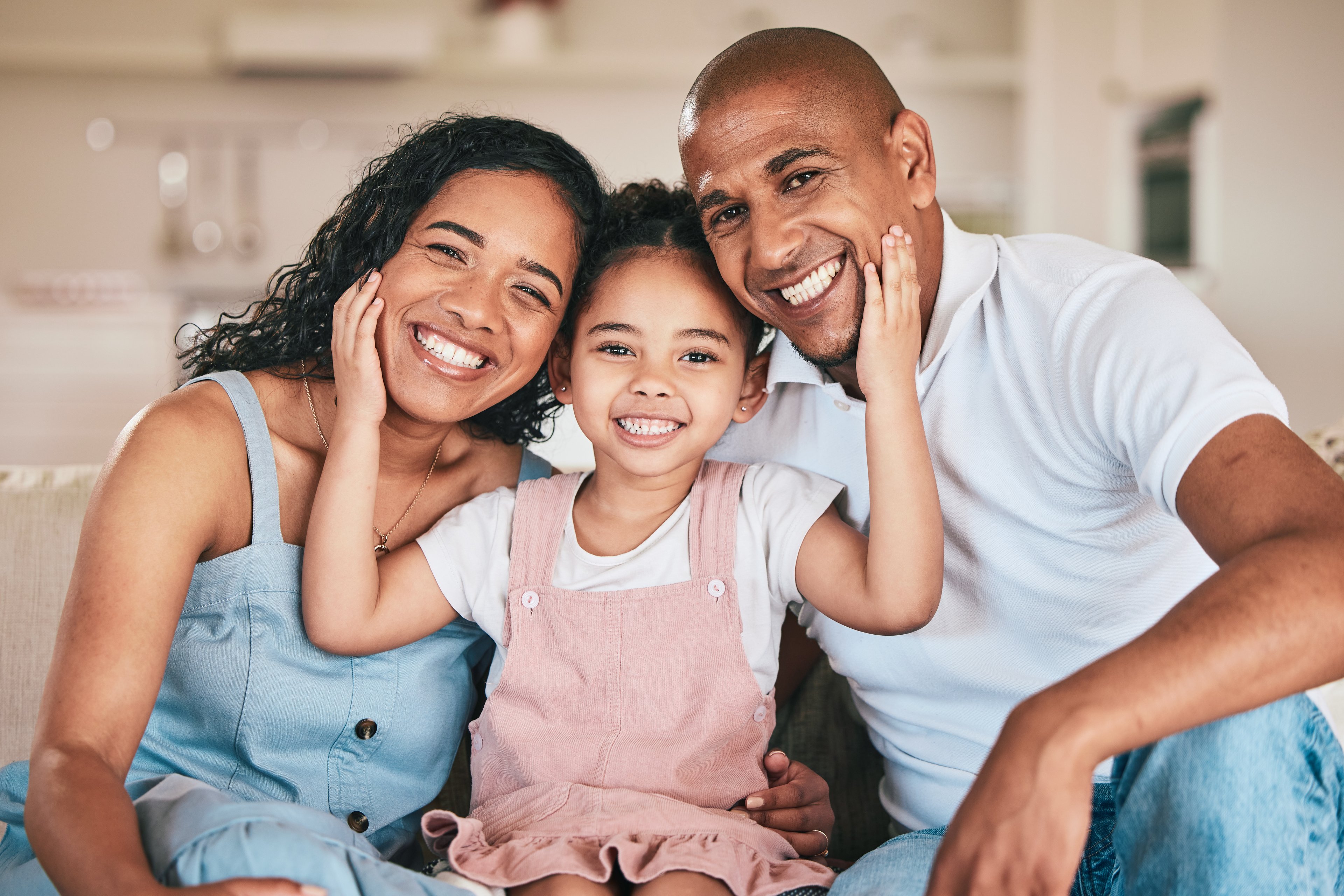 Three people together smiling while the middle one has hands on the others' faces.