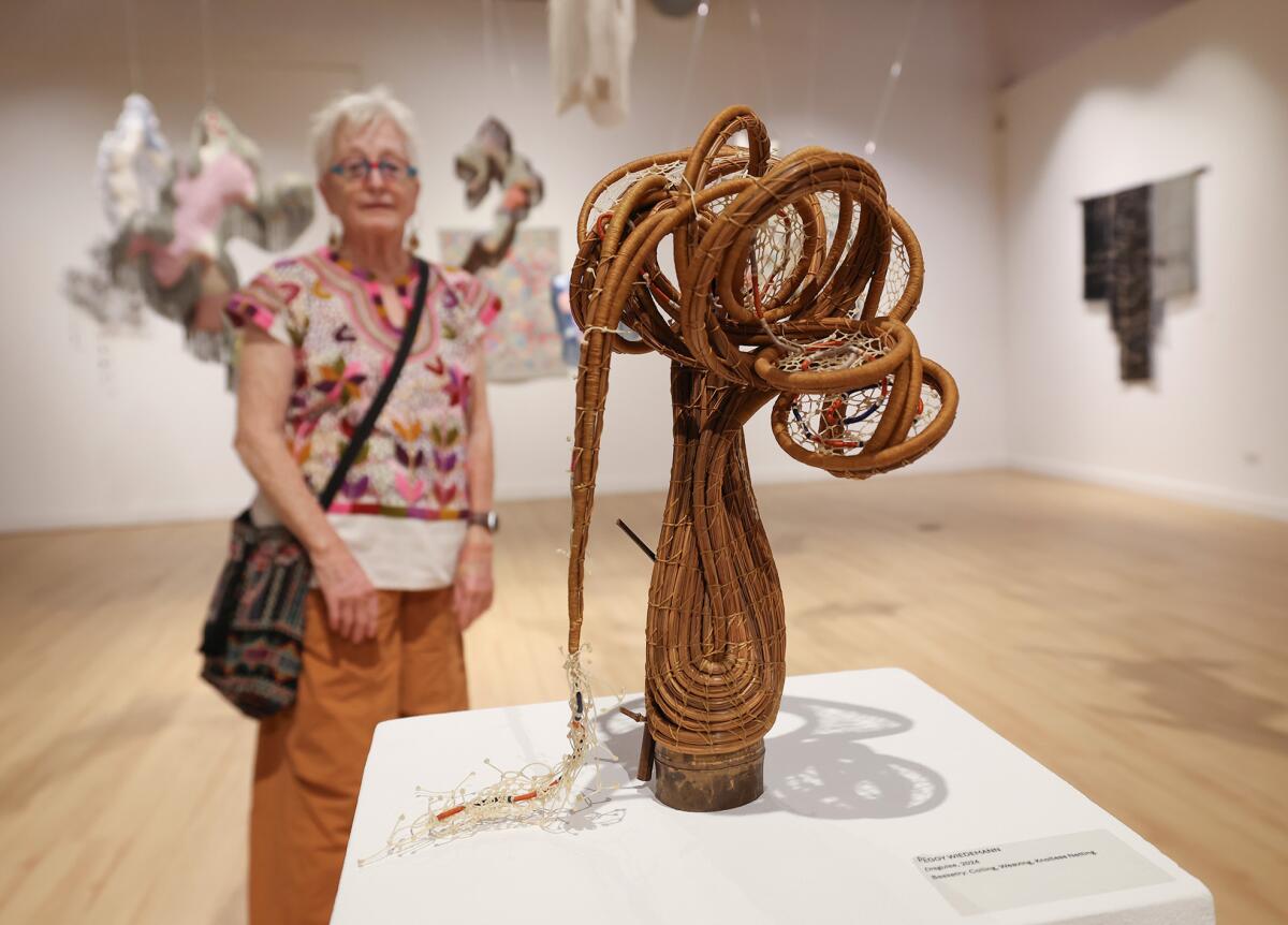 Huntington Beach artist Peggy Wiedemann stands with her piece, "Disguise."