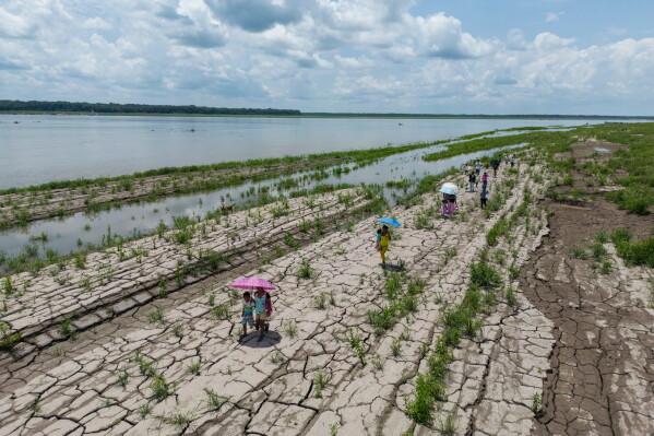 People walk through a part of the Amazon River that shows signs of drought in Santa Sofia, on the outskirts of Leticia, Colombia, Oct. 20, 2024. (AP Photo/Ivan Valencia, File)
