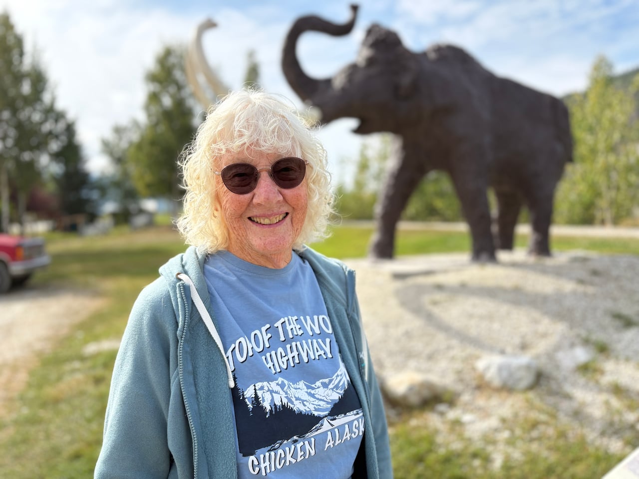 A woman standing infront of a mammoth statue.