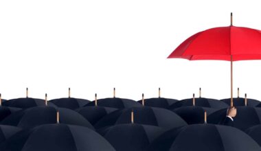 A red umbrella stands higher than a crowd of black umbrellas.