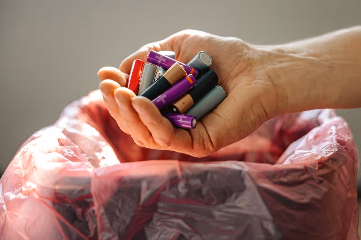 Man holding batteries in front of bin