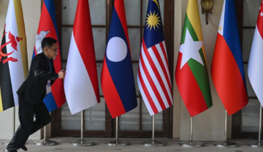 A man runs past national flags of ASEAN member states on May 5 outside a media center in Cebu, the Philippines, ahead of the 48th ASEAN Summit.